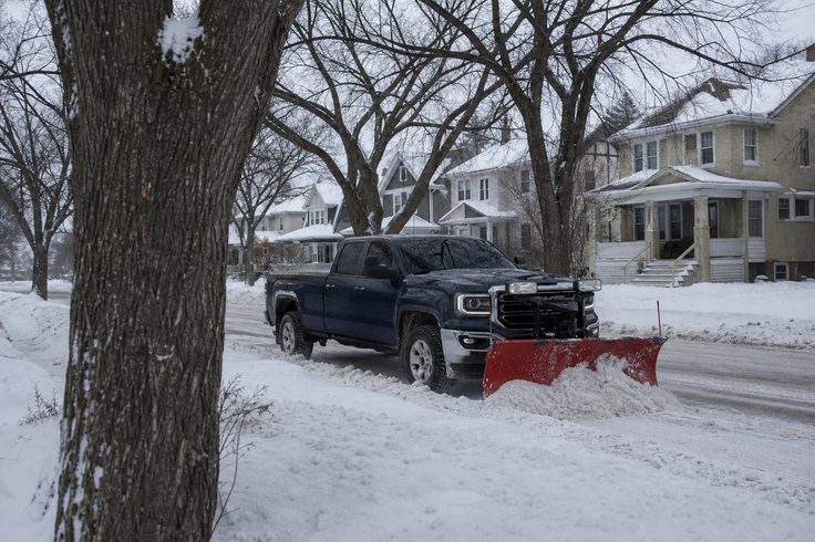 Snow plow truck at the end of a cleared Winnipeg driveway